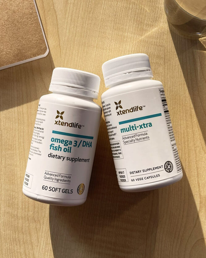 Two bottles of xtendlife supplements on a wooden surface