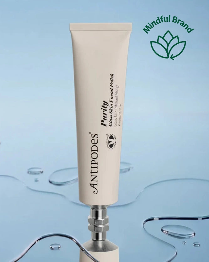 Antipodes Purity Glass Skin Facial Polish in a white tube on a mirror surface with water.