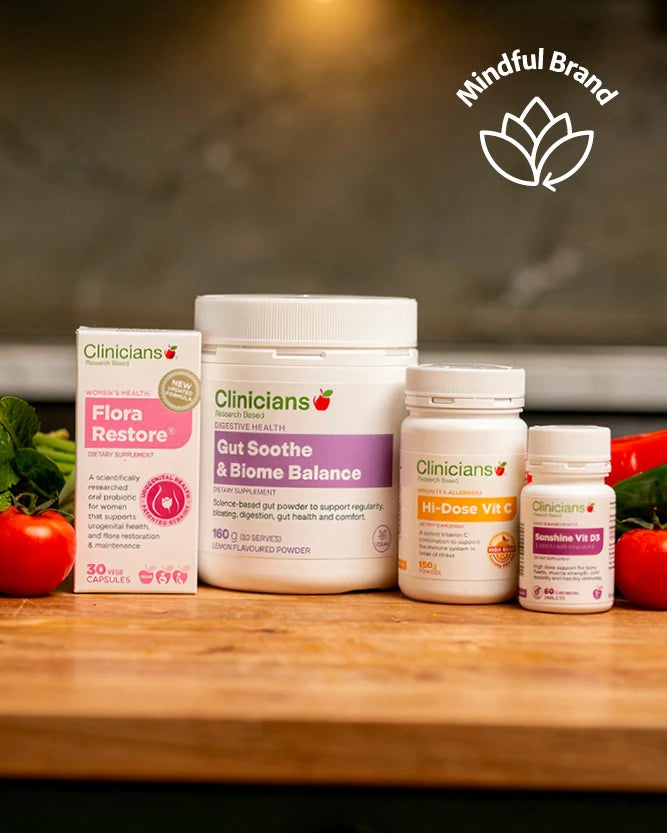 Four Clinicians brand wellness products arranged on a wooden surface with tomatoes and herbs in the background: Flora Restore, Gut Soothe & Biome Balance, MR-Dose VIT C, and Gut Health Kit. A 'Mindful Brand' logo appears in the top right.