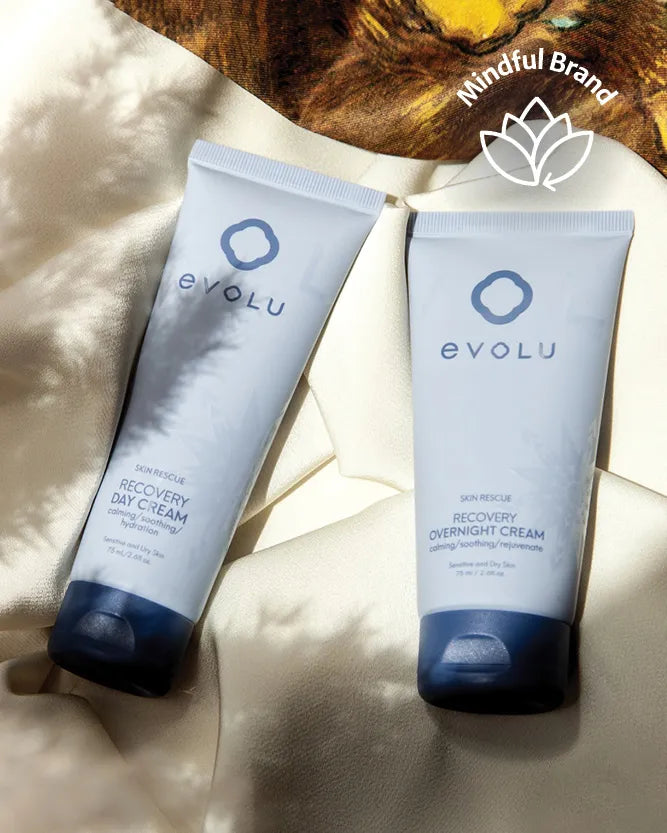 Two Evolu skincare tubes, one Recovery Day Cream and one Overnight Cream, displayed on a draped cream fabric with leaf shadows. A wooden slice and 'Mindful Brand' logo are visible in the background.