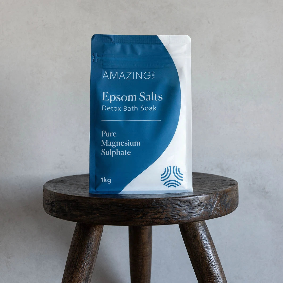 Bag of Epsom salts on a wooden stool against a grey background