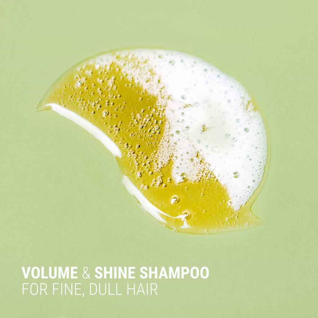 Shampoo with volume and shine benefits on a green background.