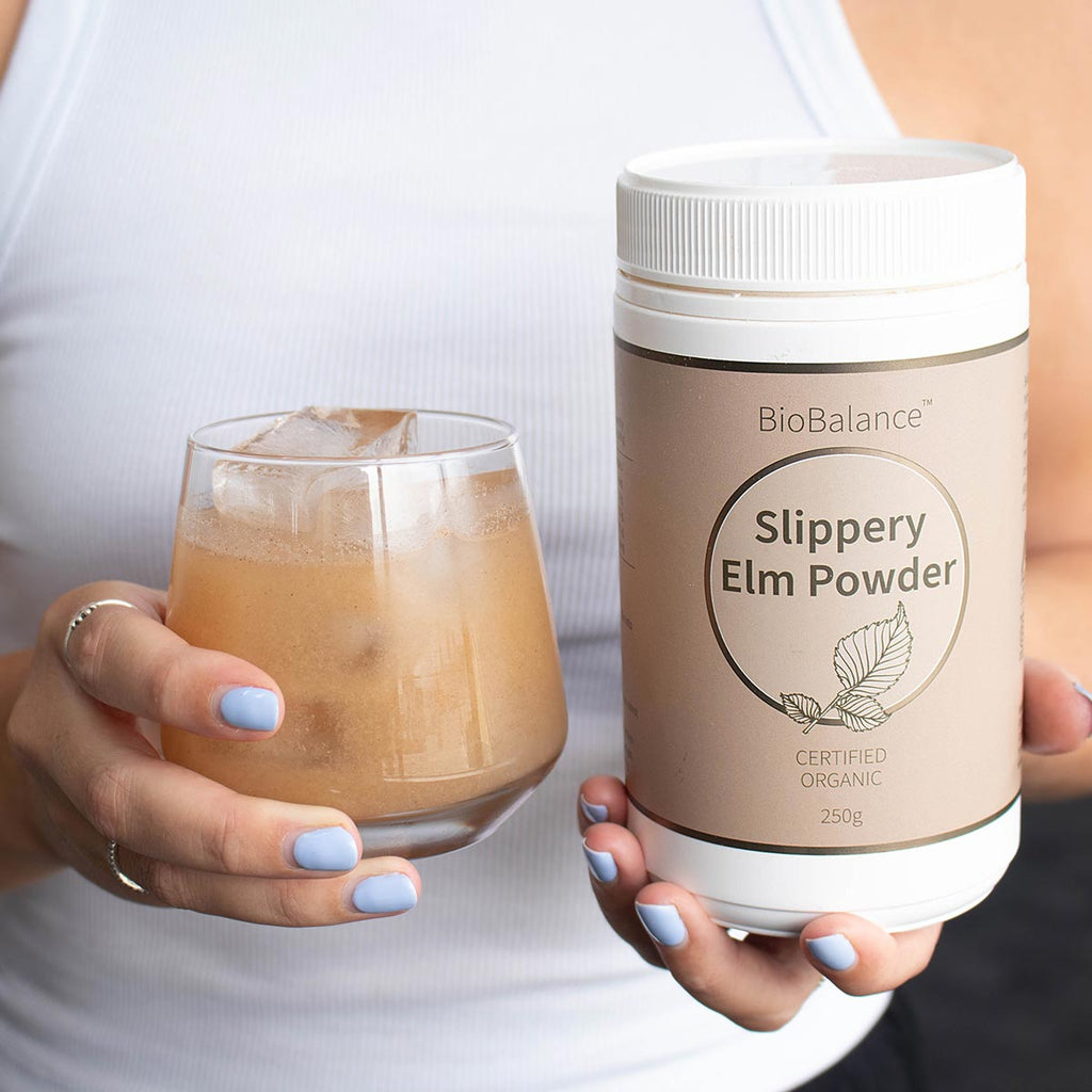 Person holding a glass of iced coffee and a container of BioBalance Slippery Elm Powder.