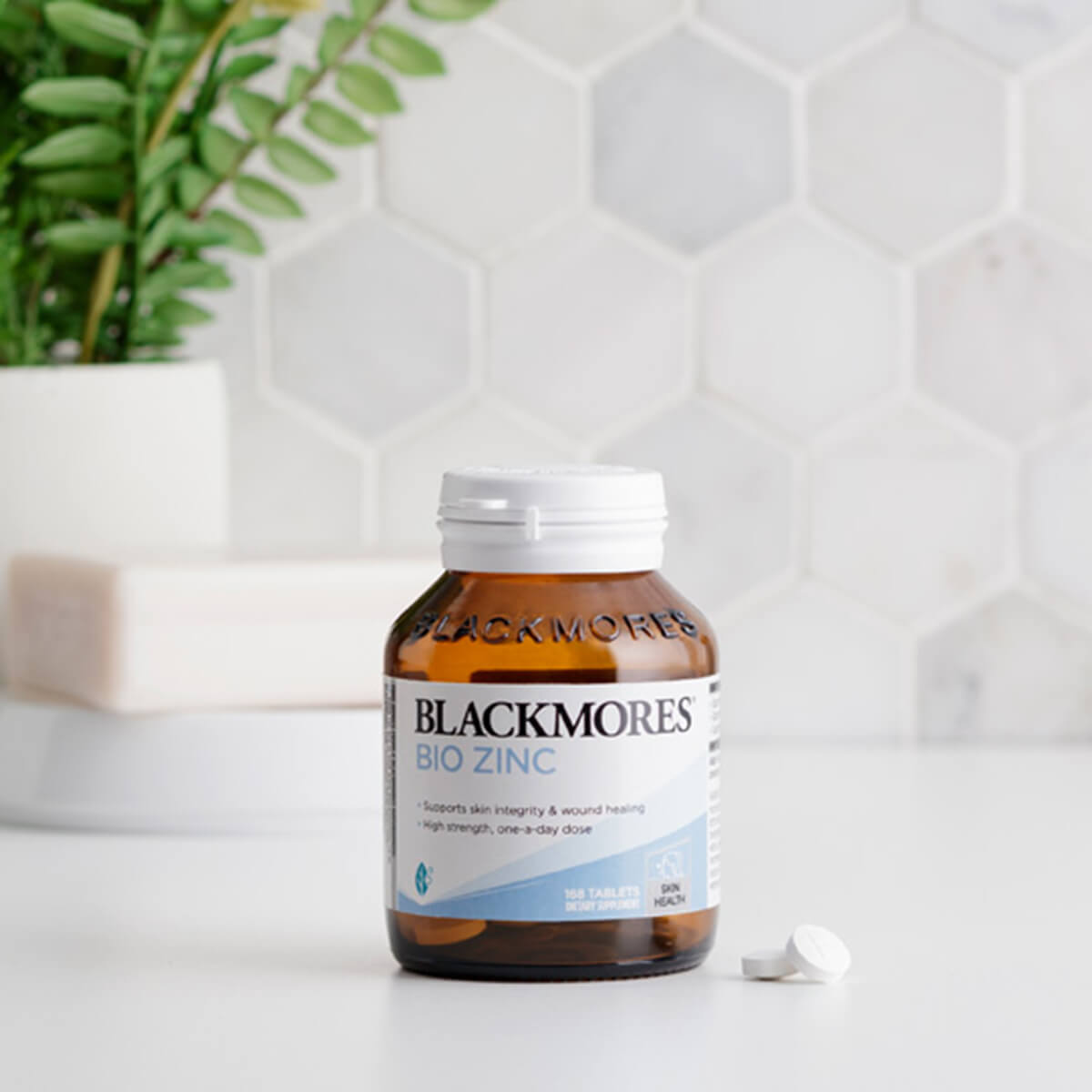 Blackmores Bio Zinc supplement bottle on a white surface with a plant in the background.