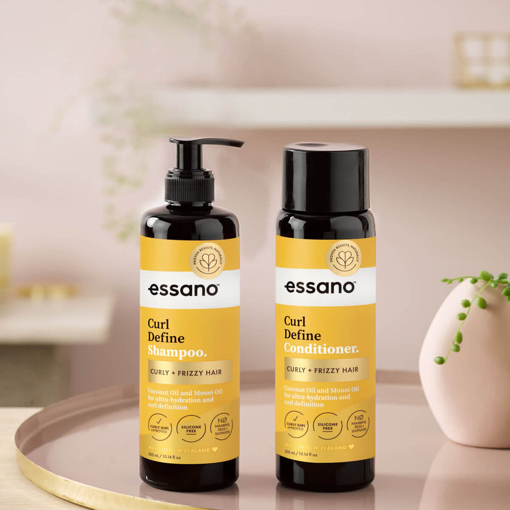 Essano Curl Define Shampoo and Conditioner bottles on a blurred background.