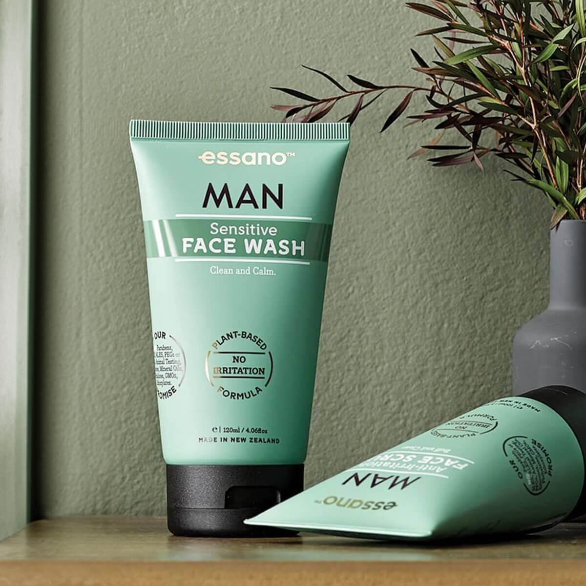 Essano Man Sensitive Face Wash tube on a wooden surface with a plant in the background.