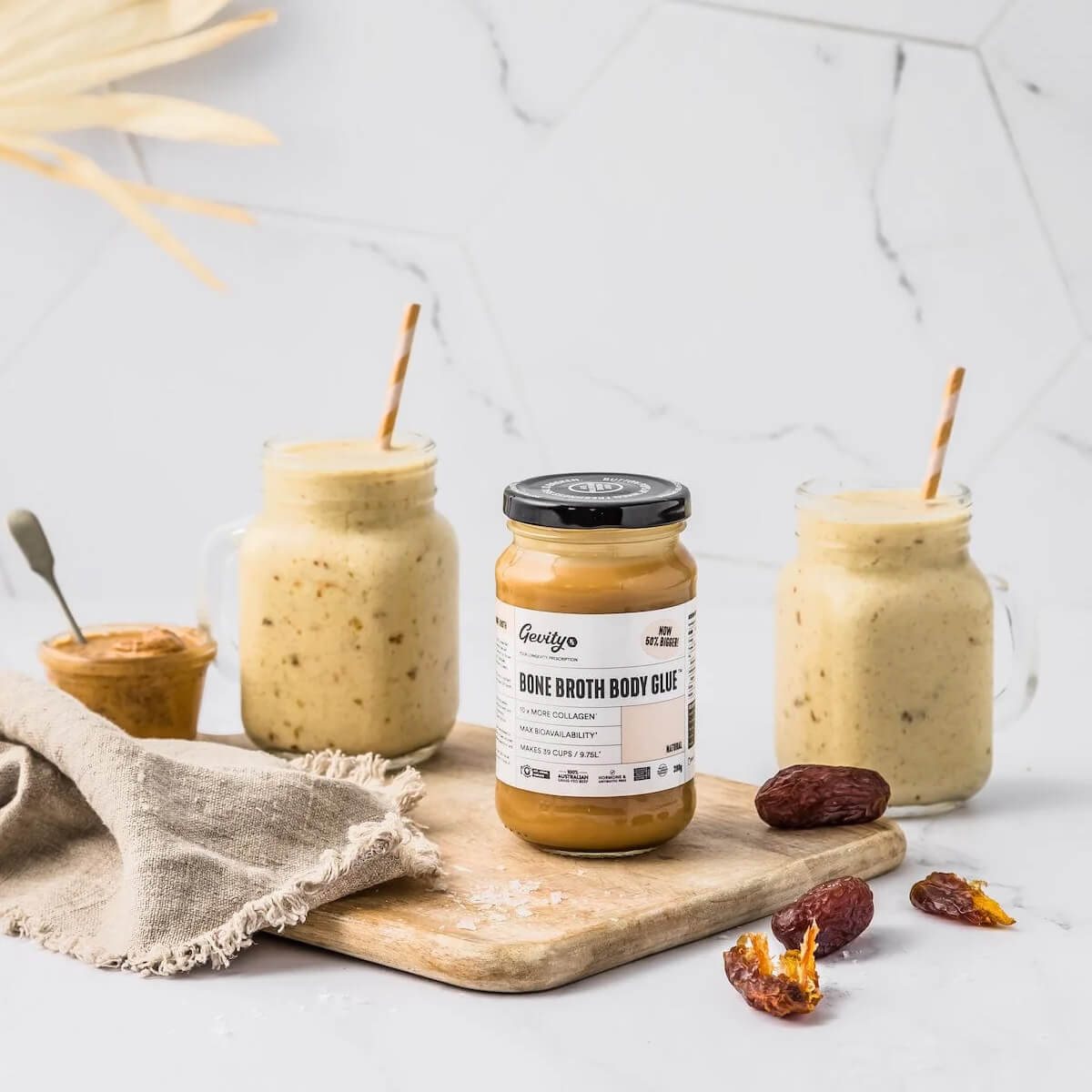 Jar of 'Bone Broth Body Glue' with two smoothies on a wooden board.