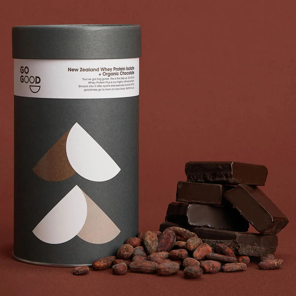 Chocolate whey protein isolate container against a maroon background with cocoa beans and chocolate slabs.