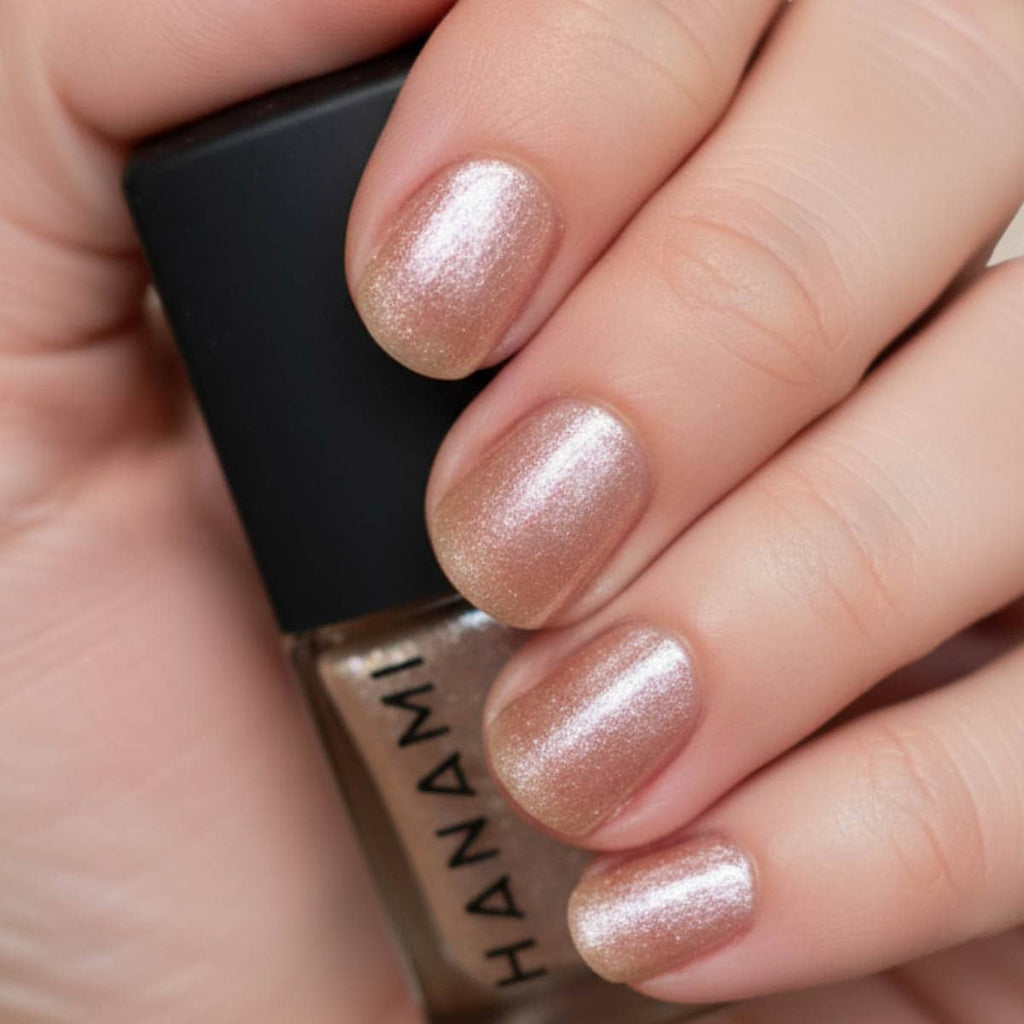 Close-up of a hand with glittery nail polish holding a bottle of Hanami nail polish.