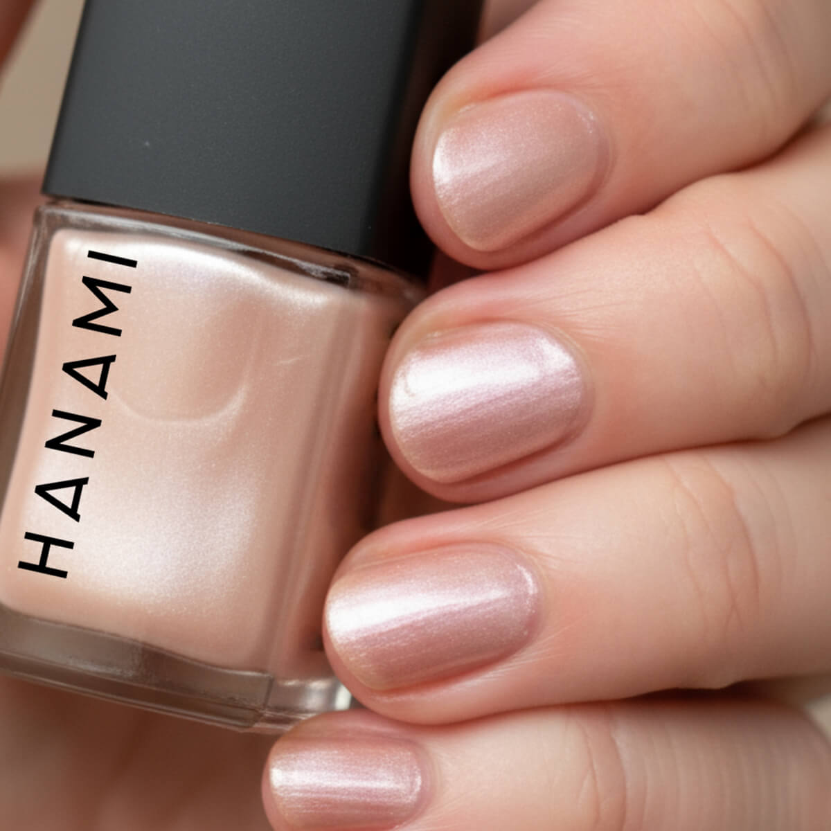 Hand holding a bottle of HANAMI nail polish with a close-up of nails painted with the same polish.