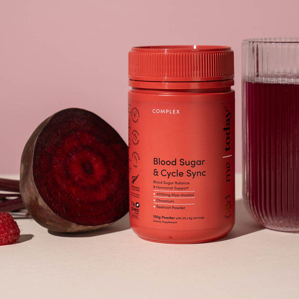 Red supplement bottle labeled 'Blood Sugar & Cycle Sync' with a beetroot and raspberries on a pink background