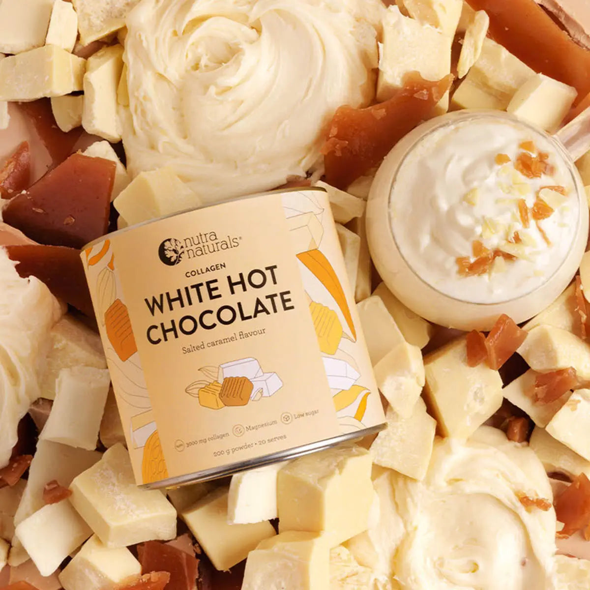 Collagen White Hot Chocolate mix surrounded by white chocolate pieces and a small cup of hot chocolate.