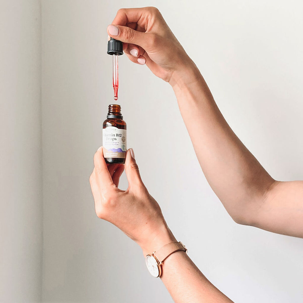 Hand holding a dropper bottle with a neutral background.